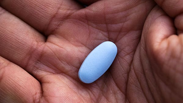 Man holding an erectile dysfunction medication pill