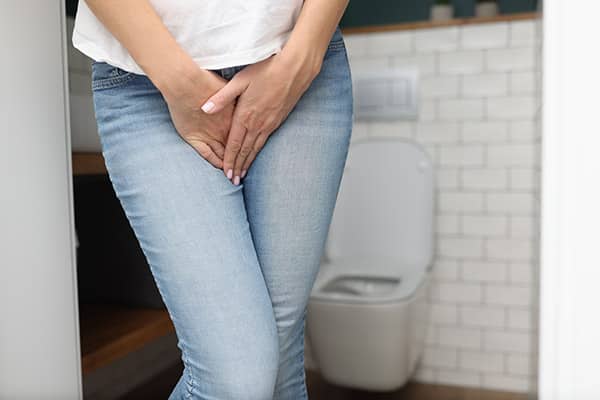 Female hands between legs in jeans close-up. Diagnosis and treatment of sexually transmitted diseases concept.