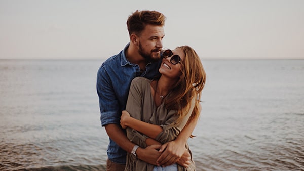 Modern couple on the beach hugging and loving each other